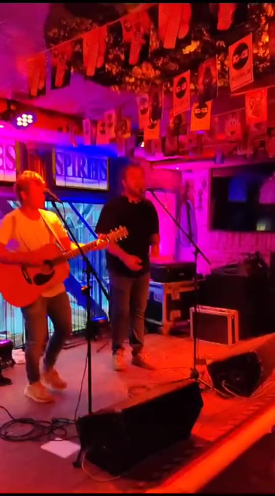 Zanger Mark Schokker zingt met akoestische begeleiding in een bar met roze en rood licht